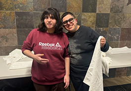  two students pose for picture while folding a towel