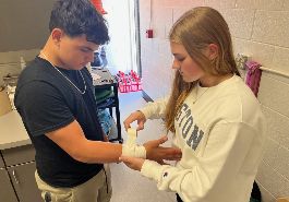 Medical science student taping jv athlete